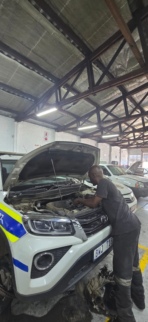 Mechanic working under the bonnet of a vehicle in the workshop